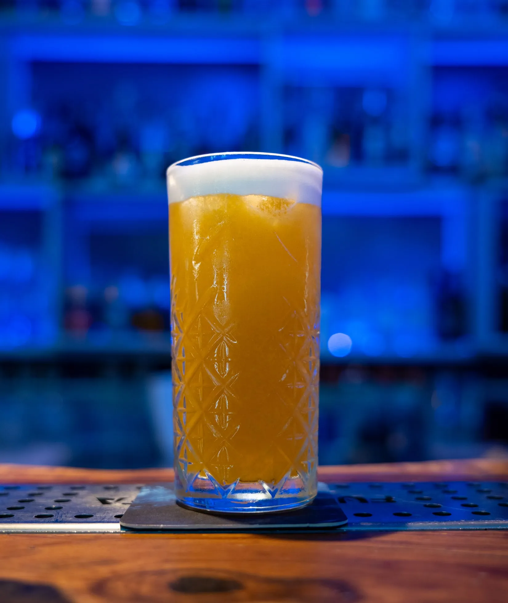 Un long drink arancione con la schiuma, sul bancone