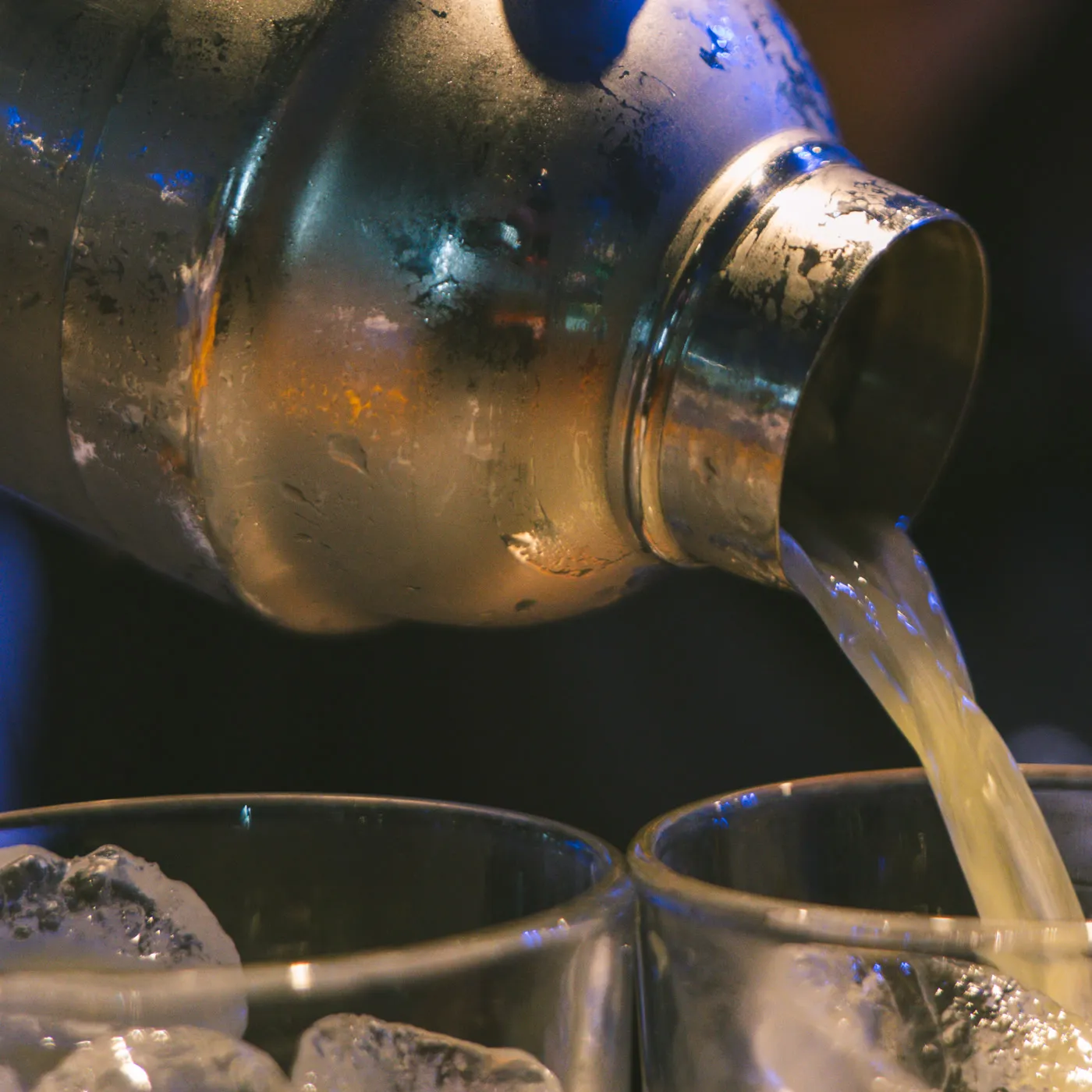 Lo shaker versa il cocktail nei due bicchieri col ghiaccio